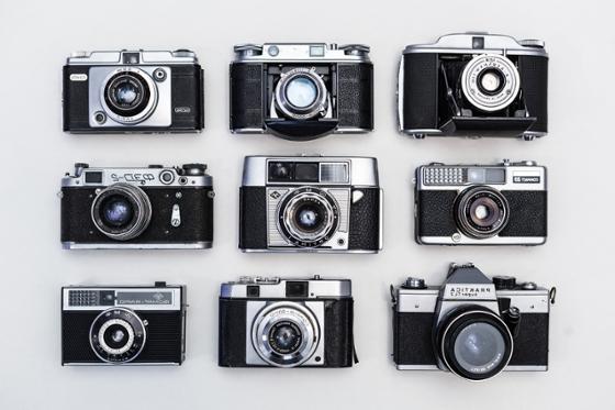 Photo of nine black film cameras are arranged in a square.