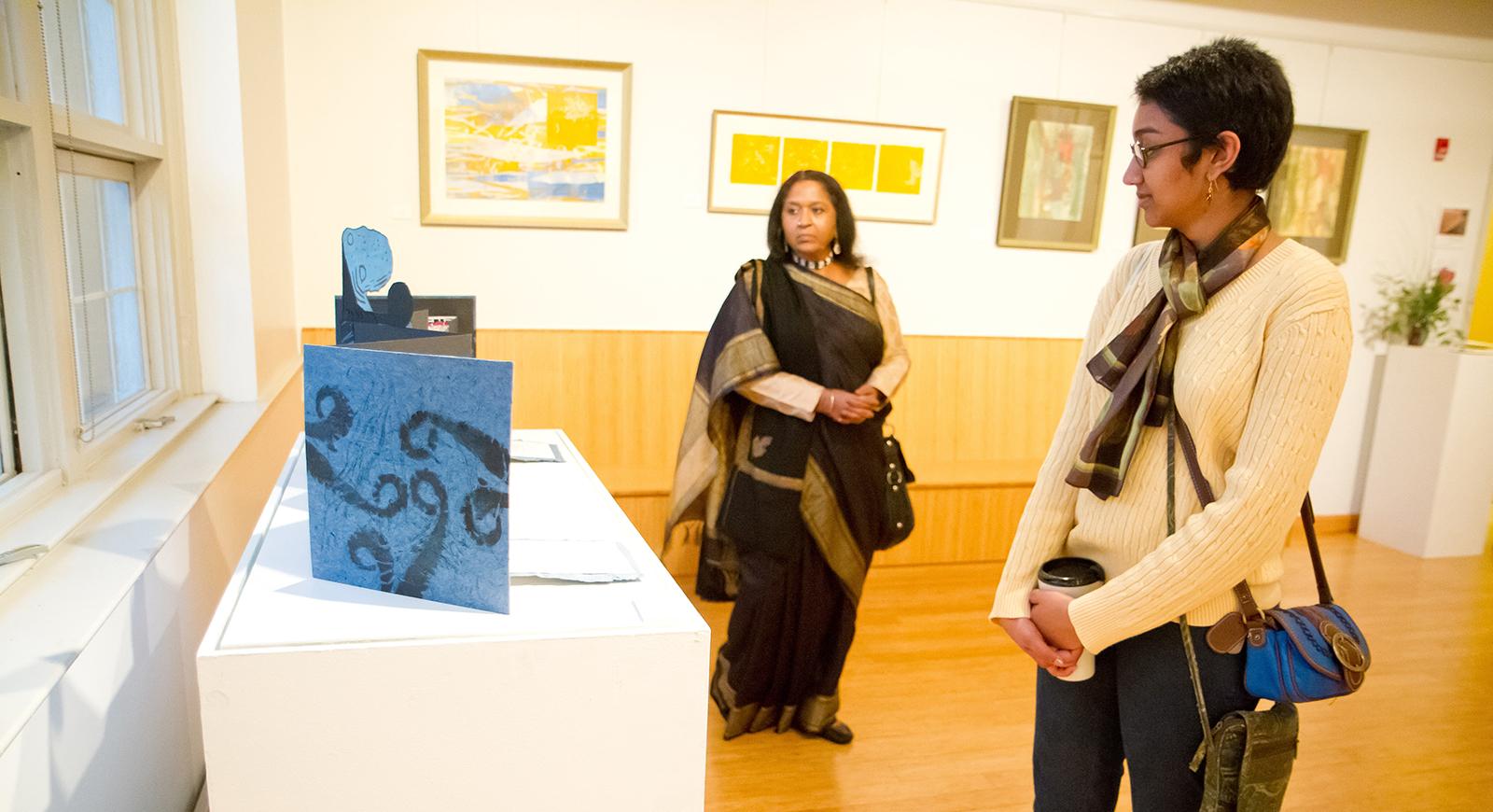 Photo of two women walking around Chatham University's media arts gallery looking at installations. 