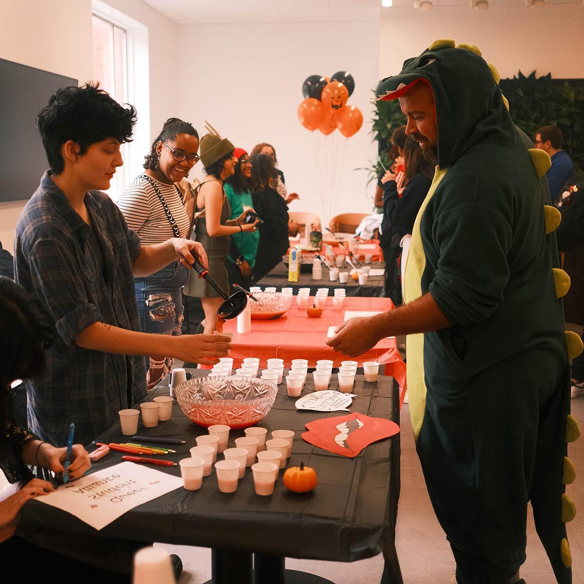 Photo of students in Halloween costumes serving and receiving mocktails